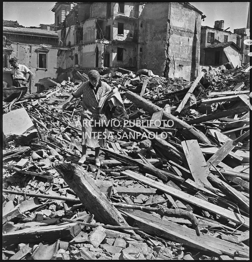 Una donna cammina sulle macerie degli edifici di via Alciato, a Milano, distrutti dai bombardamenti