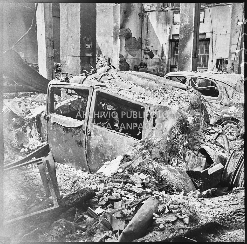 Due automobili bruciate a causa dei bombardamenti, a Milano, all'interno di un edificio ingombro di macerie