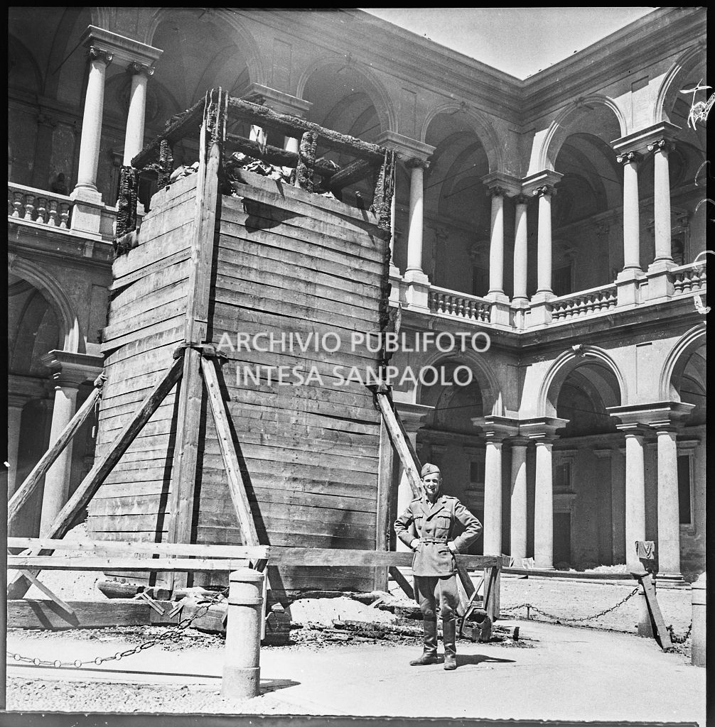Un militare posa, nel cortile d'onore del Palazzo di Brera a Milano, vicino alla statua di Napoleone Bonaparte scampata ai bombardamenti grazie all'ingabbiatura di legno e ai sacchi di sabbia messi a protezione preventiva