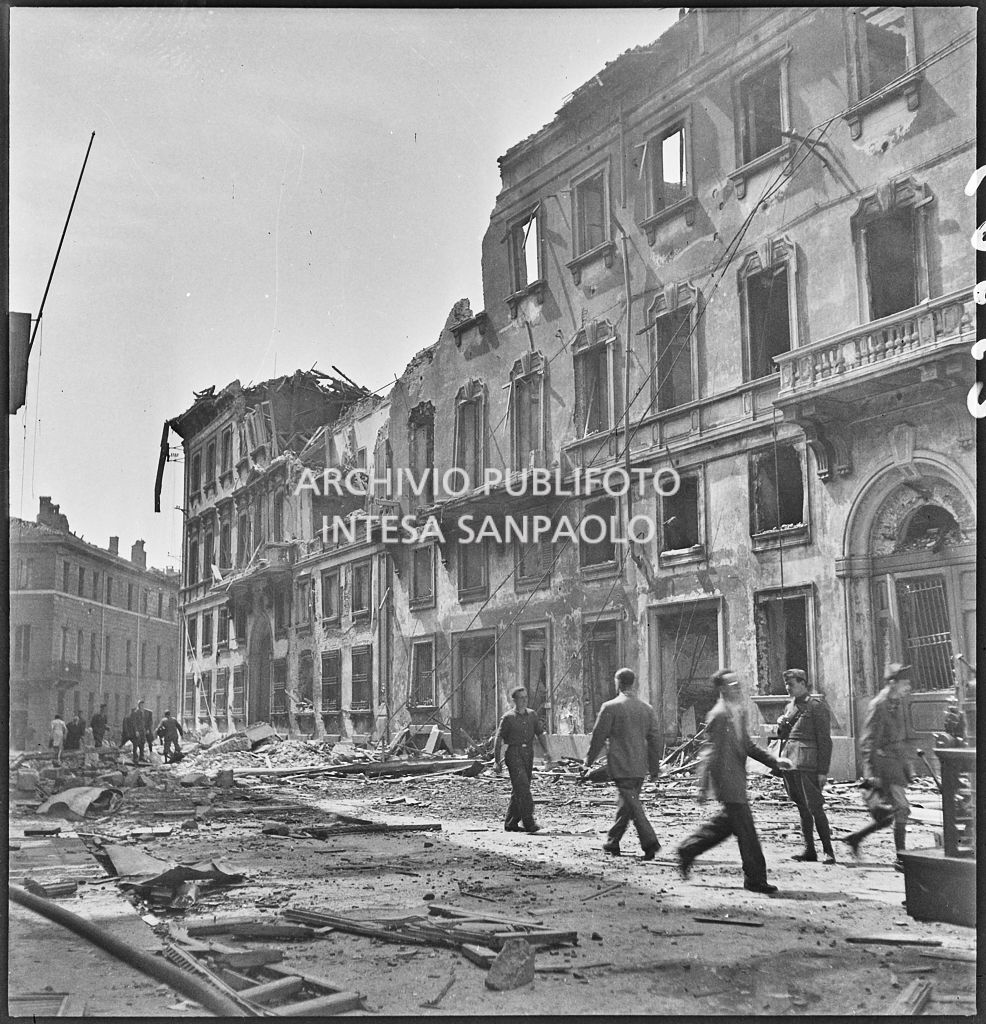 Passanti e militari camminano tra le macerie in via Brera a Milano dopo i bombardamenti