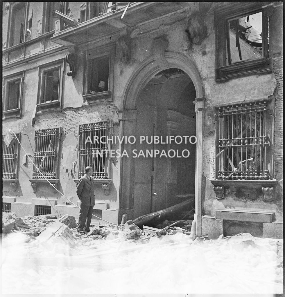 Un uomo osserva l'ingresso del palazzo in via Brera 19, a Milano, devastato dai bombardamenti