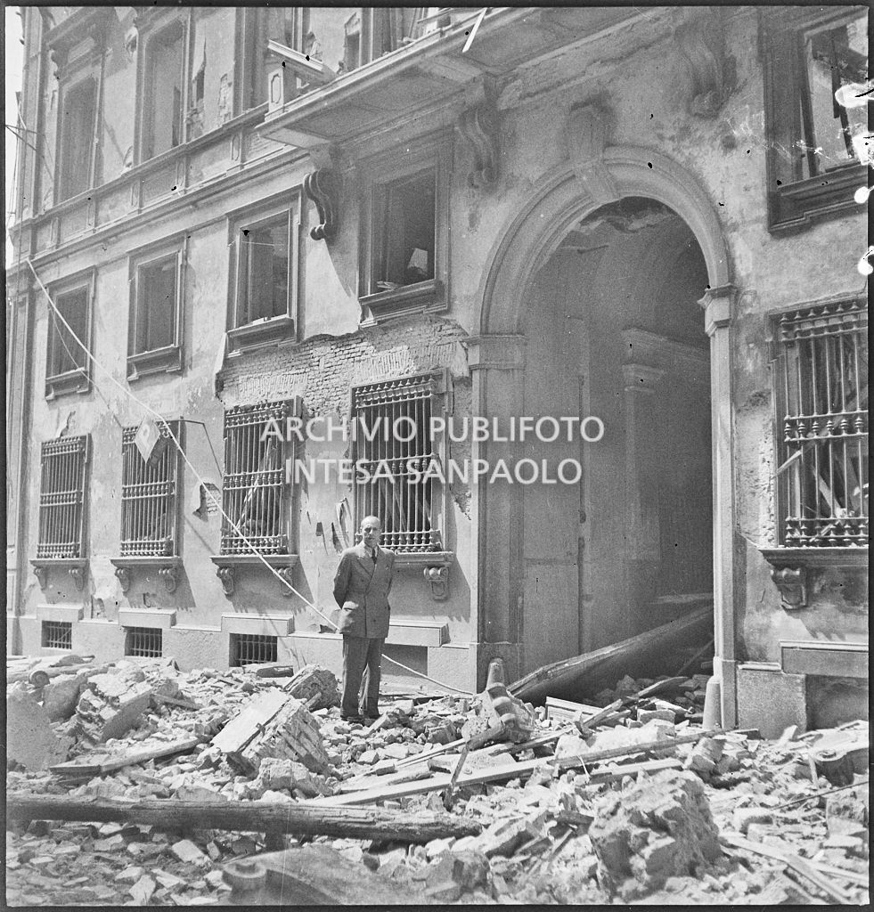 Un uomo posa tra le macerie davanti all'ingresso del palazzo in via Brera 19, a Milano, sventrato dai bombardamenti