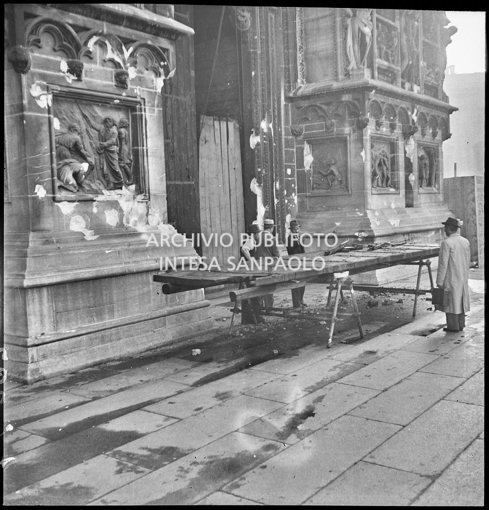 Pannello a protezione del portale del Duomo di Milano, danneggiato durante i bombardamenti, in riparazione sul sagrato del Duomo.