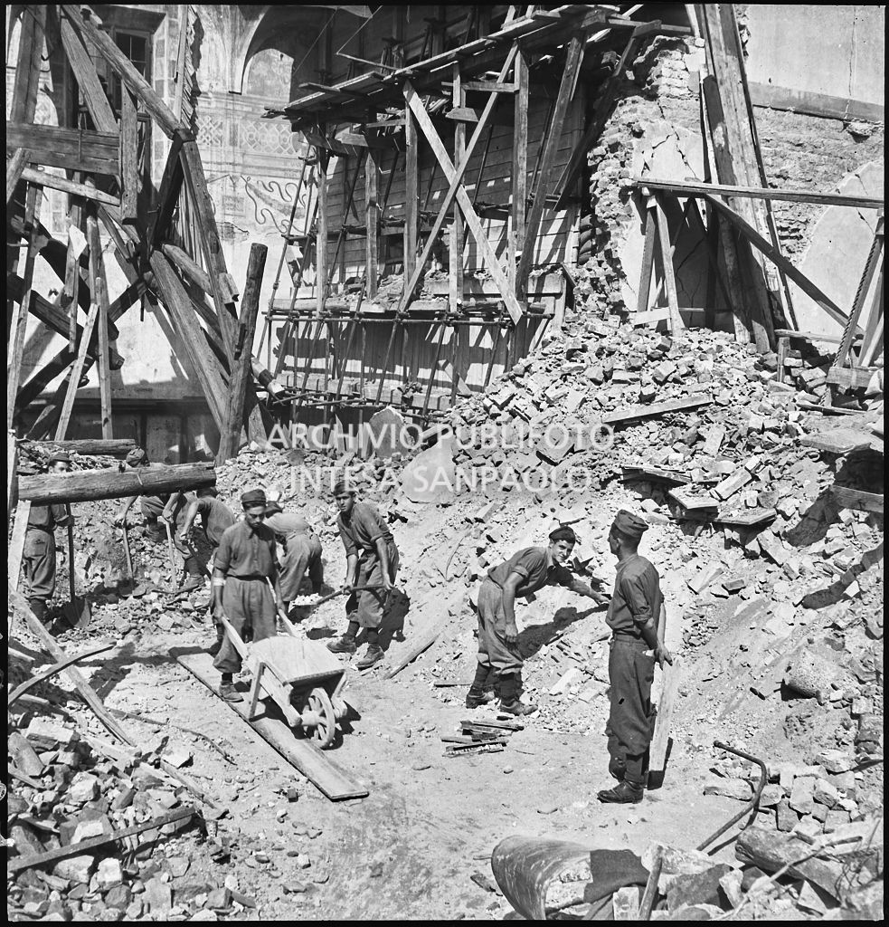 Lavori di rimozione delle macerie della basilica di Santa Maria delle Grazie a Milano dopo i bombardamenti; sullo sfondo sono visibili le impalcature di legno, i sacchi di sabbia, e i rinforzi metallici, su entrambi lati della parete settentrionale del refettorio del convento annesso alla basilica, messi a protezione del Cenacolo vinciano che lo salvaguardarono