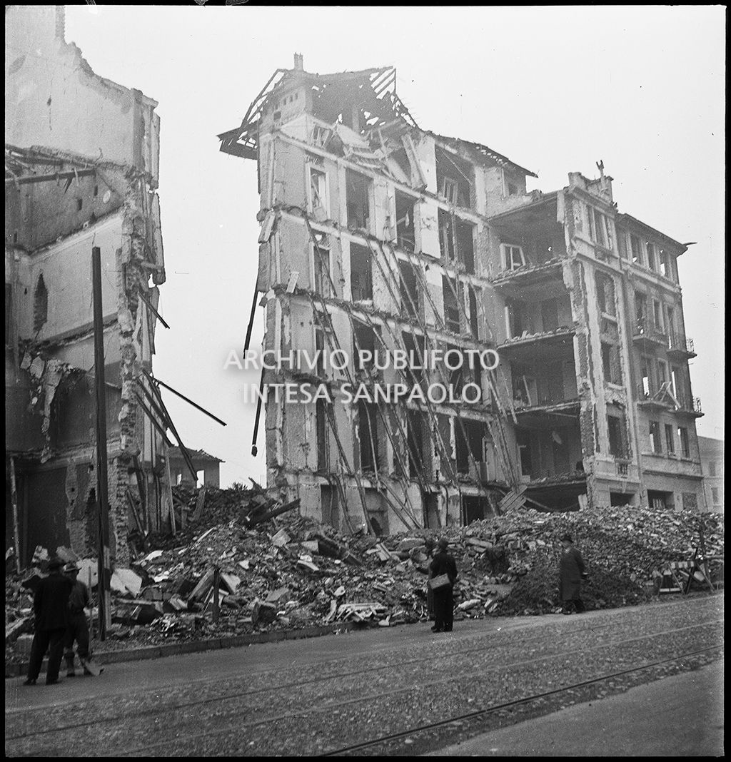 Muro di spina superstite di un edificio quasi totalmente distrutto dai bombardamenti nella zona di via Mac Mahon a Milano; per strada alcuni passanti