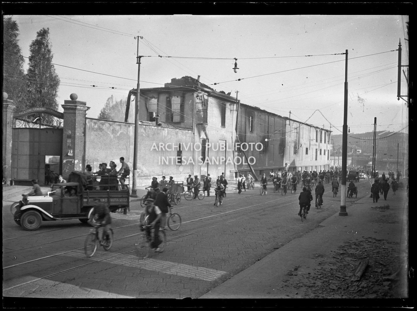 Persone, in via Carlo Farini a Milano, nei giorni dei bombardamenti, lasciano la città con ogni mezzo: a piedi, in bicicletta o con automobili