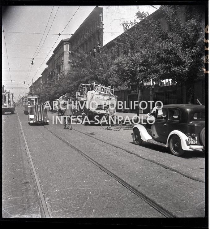 Esodo dalla città, dopo i bombardamenti di Milano, con carri, trainati da cavalli, carichi di masserizie; dietro al tram tipo 1928 un'automobile con le bombole a metano per la carenza di benzina