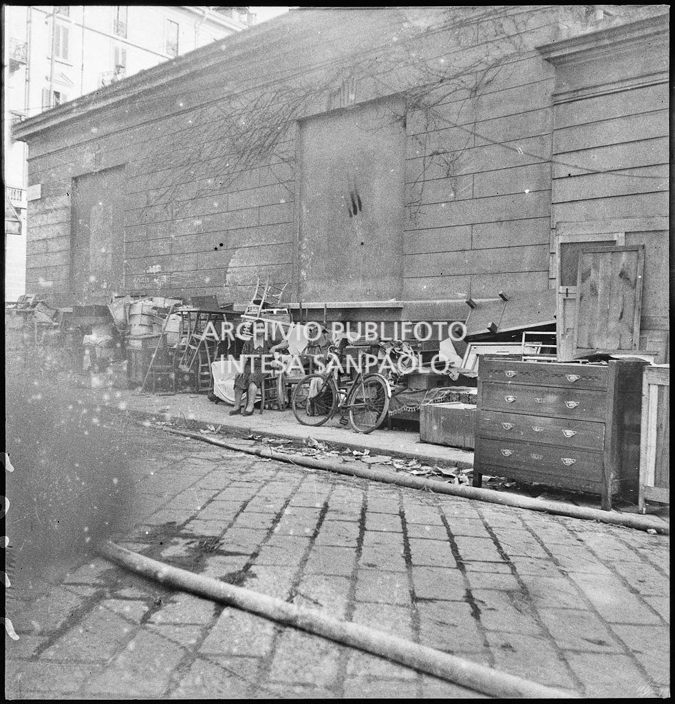 Una donna siede su una seggiola per strada insieme alle masserizie recuperate, dalle abitazioni, dopo i bombardamenti della città