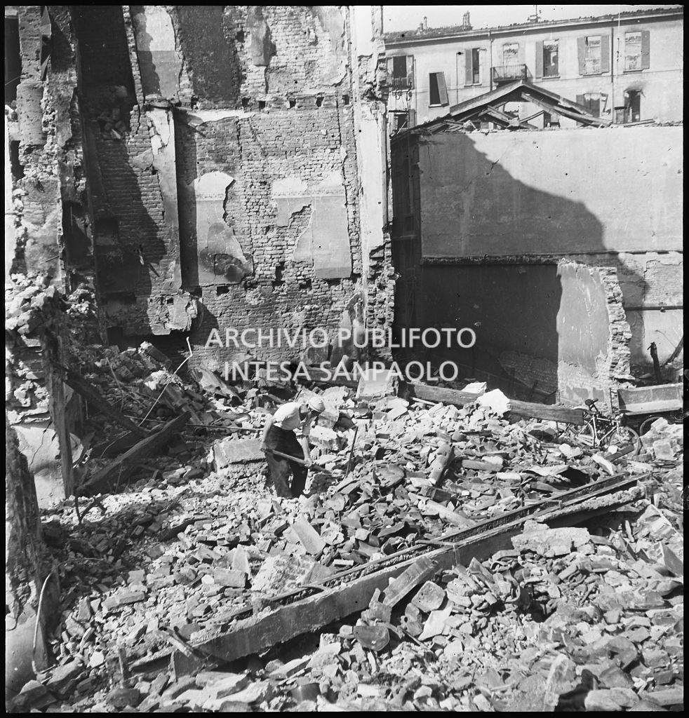 Un uomo e una donna tra le macerie degli edifici distrutti dai bombardamenti in via Beno de' Gozzadini (via che oggi non esiste più, collegava corso Italia all'allora corso Roma, oggi corso di Porta Romana)