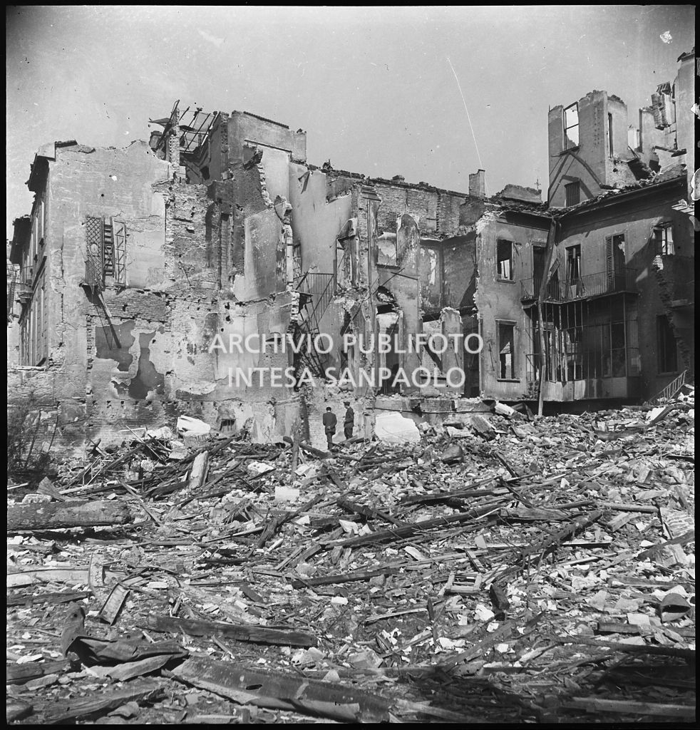Due uomini tra le macerie degli edifici distrutti dai bombardamenti in via Beno de' Gozzadini  (via che oggi non esiste più, collegava corso Italia all'allora corso Roma, oggi corso di Porta Romana)