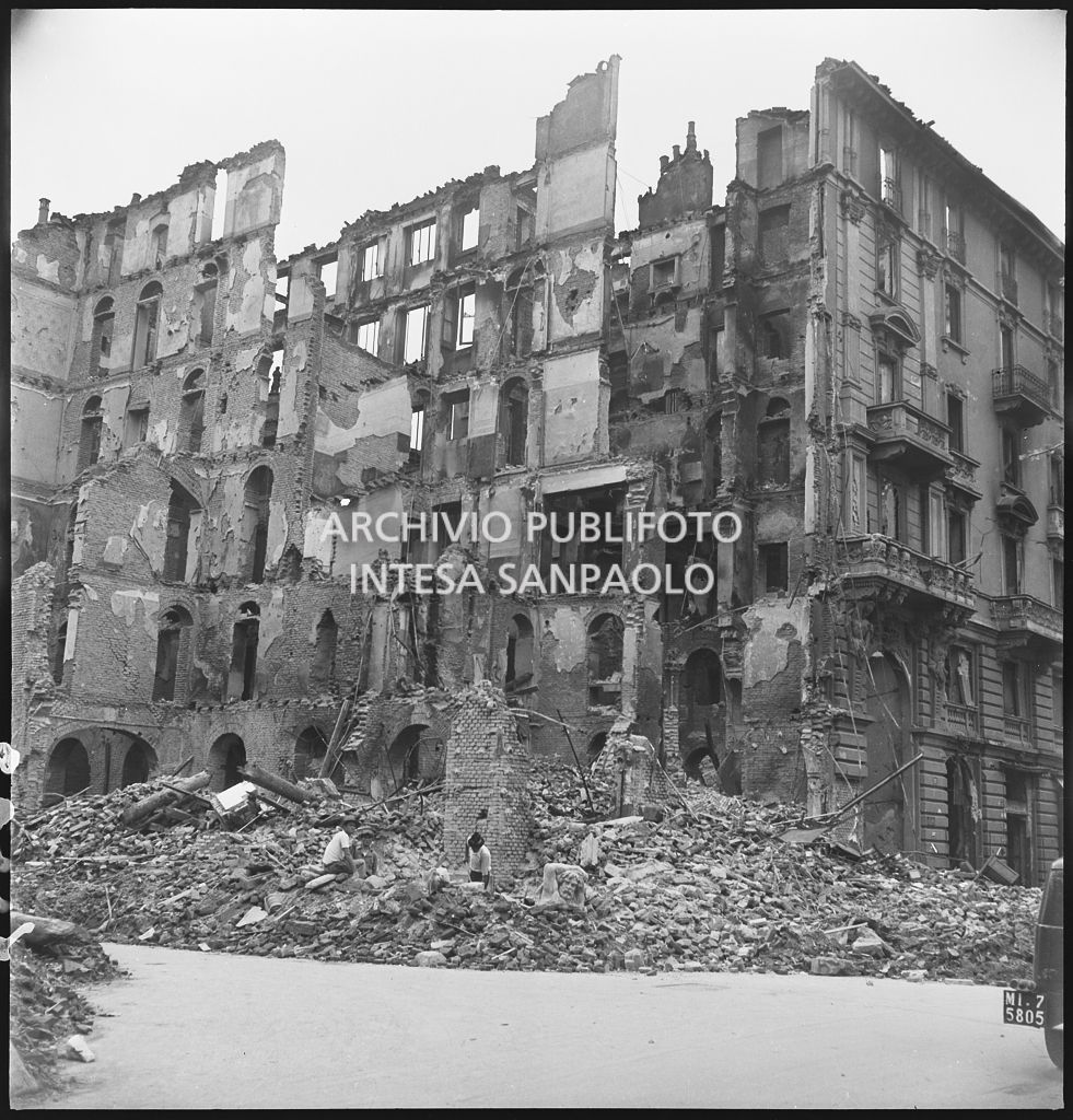 Due uomini tra le macerie dell'edificio, tra via Lecco e via San Gregorio a Milano, distrutto dai bombardamenti: si riconosce la testa di un telamone