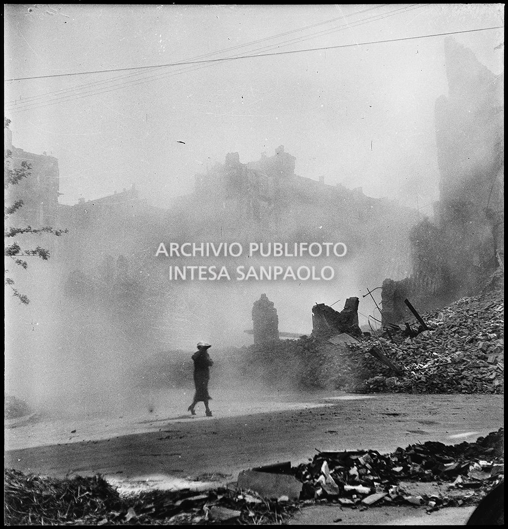 Una donna cammina in via Lecco a Milano all'indomani dei bombardamenti che hanno distrutto gli edifici della via e la cui polvere è ancora nell'aria