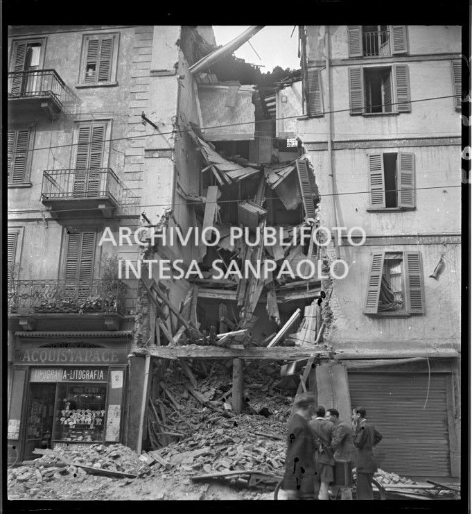 Passanti davanti a un edificio crollato a causa dei bombardamenti in via Ponte Vetero a Milano; al civico 11 la tipografia-litografia Acquistapace
