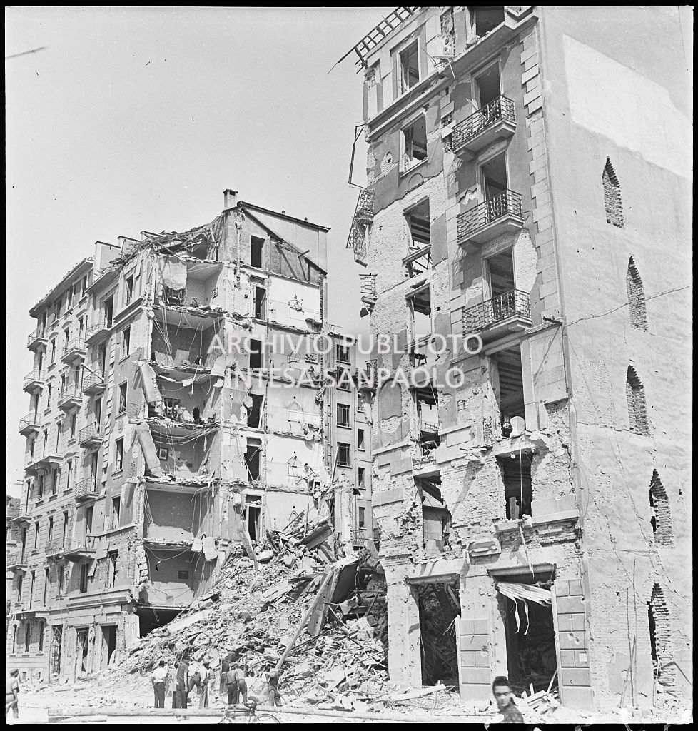 Passanti osservano gli edifici distrutti dai bombardamenti in via Luigi Canonica a Milano