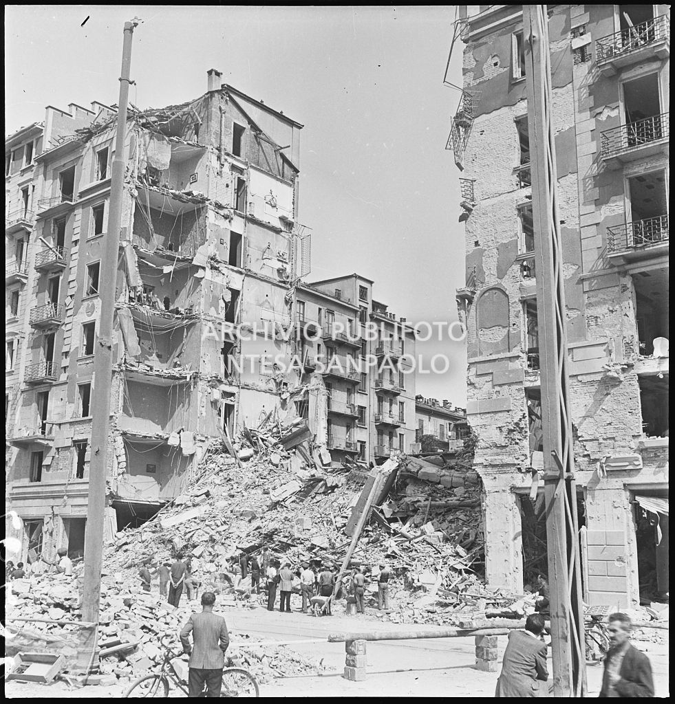Passanti osservano gli edifici distrutti dai bombardamenti in via Luigi Canonica a Milano