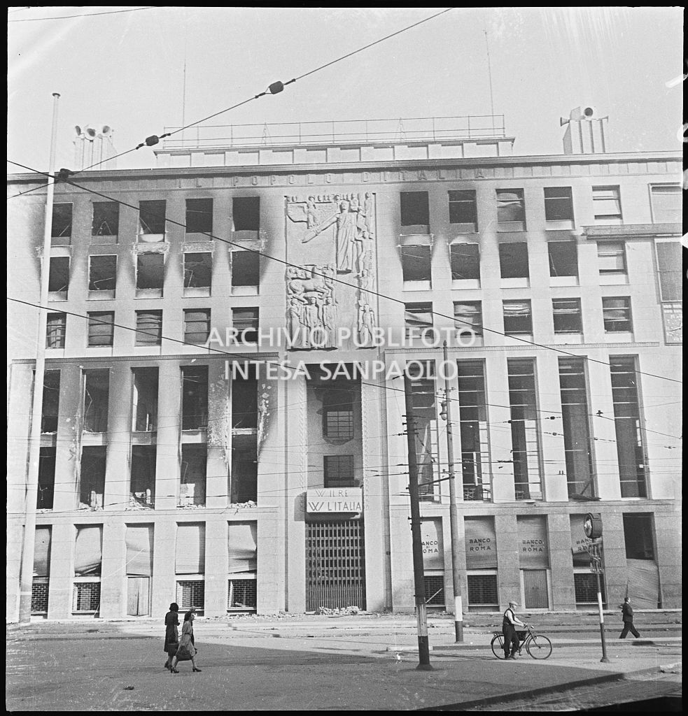 Facciata del Palazzo del Popolo d'Italia, poi Palazzo dell'Informazione, in piazza Cavour a Milano, danneggiato dai bombardamenti. Sopra l'ingresso le scritte: "W il re W l'Italia"