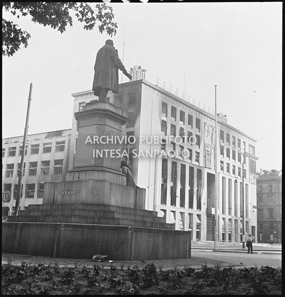 Scorcio del Palazzo del Popolo d'Italia, poi Palazzo dell'Informazione, in piazza Cavour a Milano, danneggiato dai bombardamenti. In primo piano il monumento a Camillo Benso Cavour