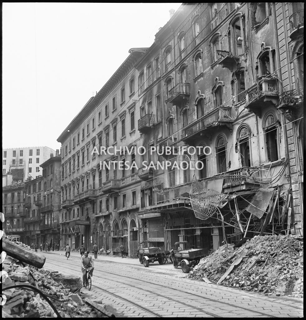 Scorcio di corso Vittorio Emanuele II a Milano dopo i bombardamenti che hanno gravemente danneggiato gli edifici che si affacciano sul corso tra cui il cinema Ambasciatori davanti al quale sono parcheggiati due autocarri