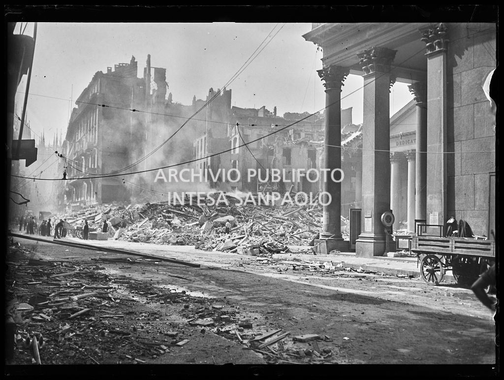 Piazza San Carlo a Milano, all'indomani dei bombardamenti, ingombra delle macerie, ancora fumanti, degli edifici e della basilica di San Carlo al Corso gravemente danneggiata durante gli attacchi aerei