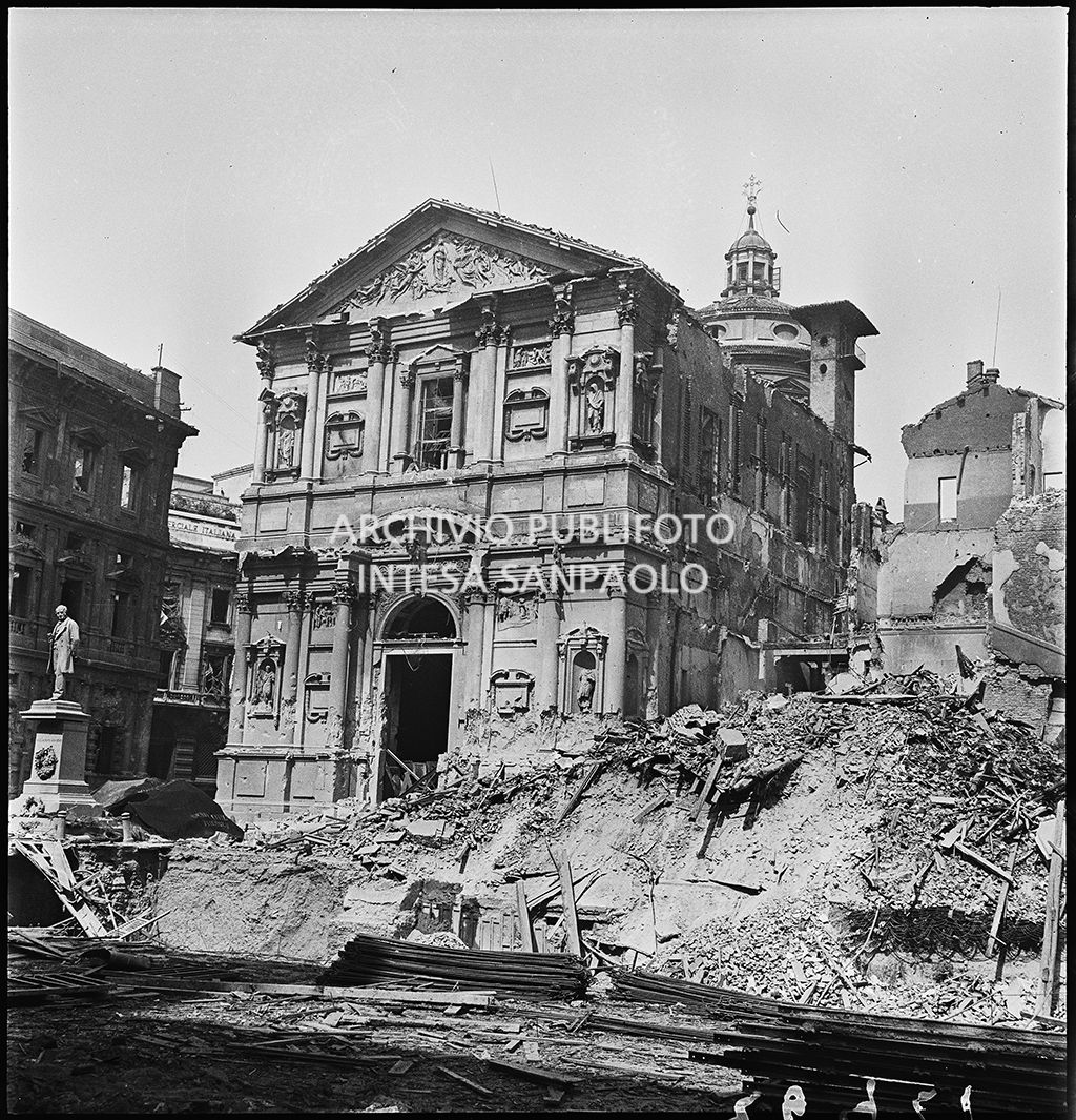 Chiesa di San Fedele, nell'omonima piazza a Milano, gravemente danneggiata dai bombardamenti; sulla destra l'edificio che ospitava la questura della città, completamente distrutto; sulla sinistra il monumento a Alessandro Manzoni intatto.