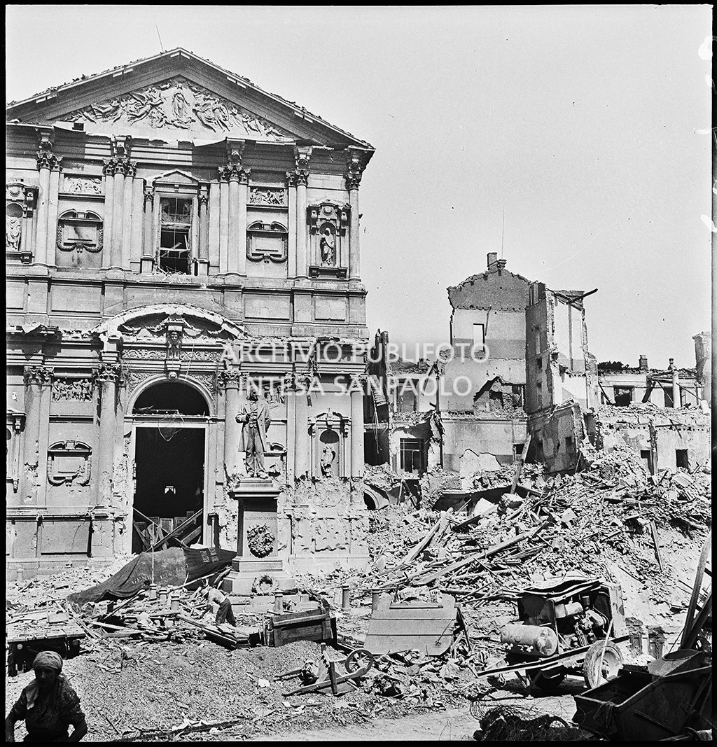 Chiesa di San Fedele nell'omonima piazza, a Milano, gravemente danneggiata dai bombardamenti; sulla destra l'edificio che ospitava la questura della città, completamente distrutto; in mezzo alla piazza il monumento a Alessandro Manzoni intatto.