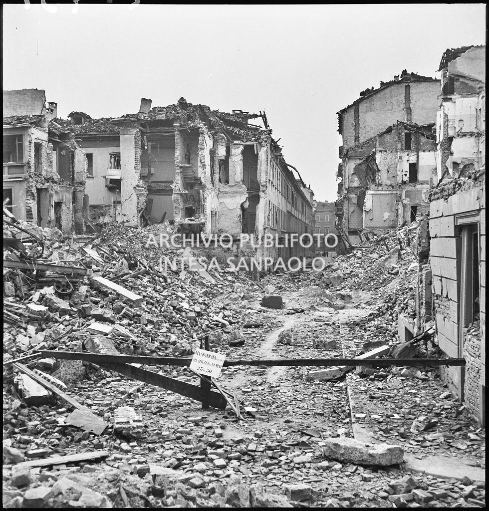 Edifici distrutti dai bombardamenti in via Santo Spirito a Milano. Sulla sbarra il cartello: "via sbarrata (via Spiga) all'altezza dei numeri 25 e 30"