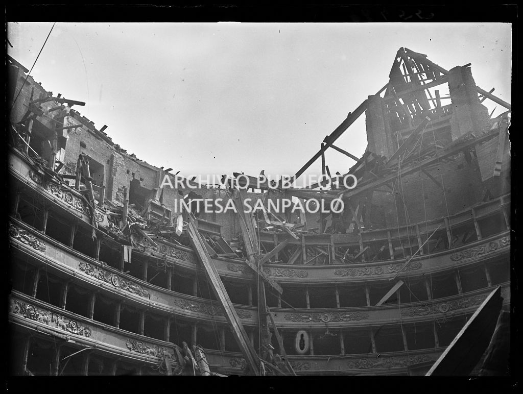 Interno del Teatro alla Scala di Milano dopo i bombardamenti: il tetto e la volta centinata sottostante sono completamente crollati distruggendo in parte il quinto e sesto ordine di gallerie e danneggiando i palchi, il proscenio e la platea