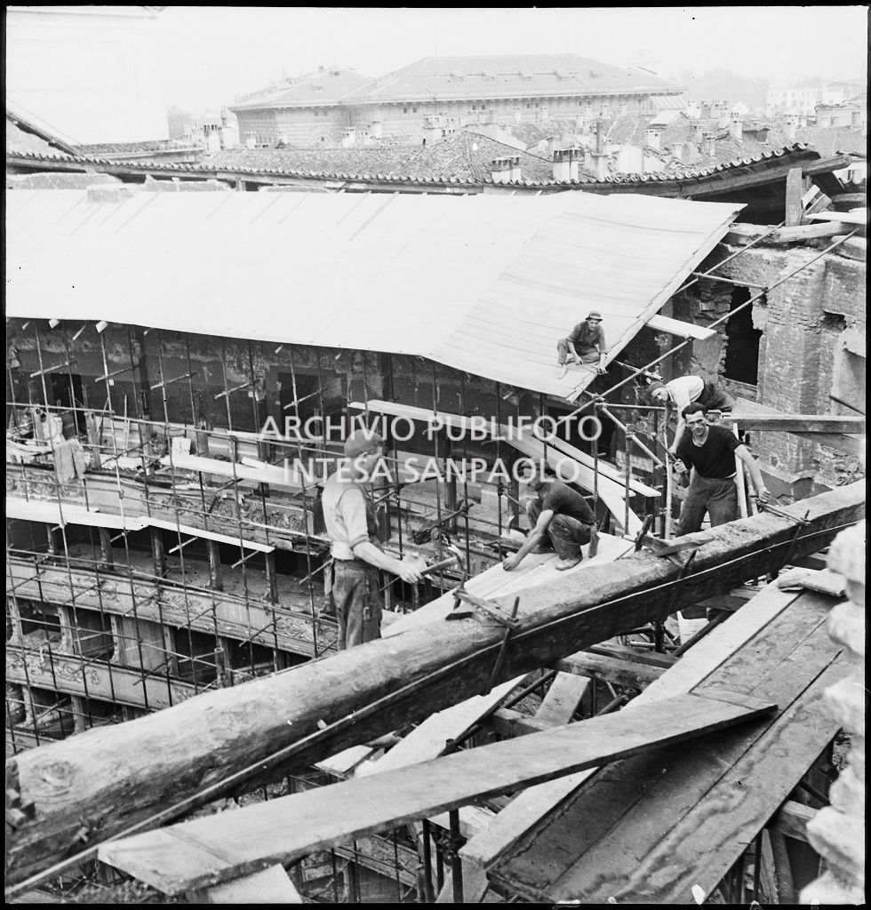 Operai al lavoro per la realizzazione di una copertura provvisoria del Teatro alla Scala di Milano, il cui tetto è crollato a causa dei bombardamenti, con una tettoia di cartone catramato sostenuta da una struttura di tubi di ferro