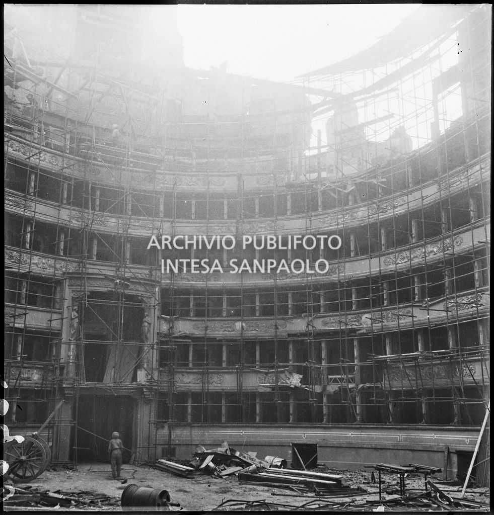Scorcio dell'interno del Teatro alla Scala di Milano gravemente danneggiato dai bombardamenti e immediatamente messo in sicurezza con una struttura di tubi metallici, dopo aver rimosso le macerie. A sinistra il palco reale