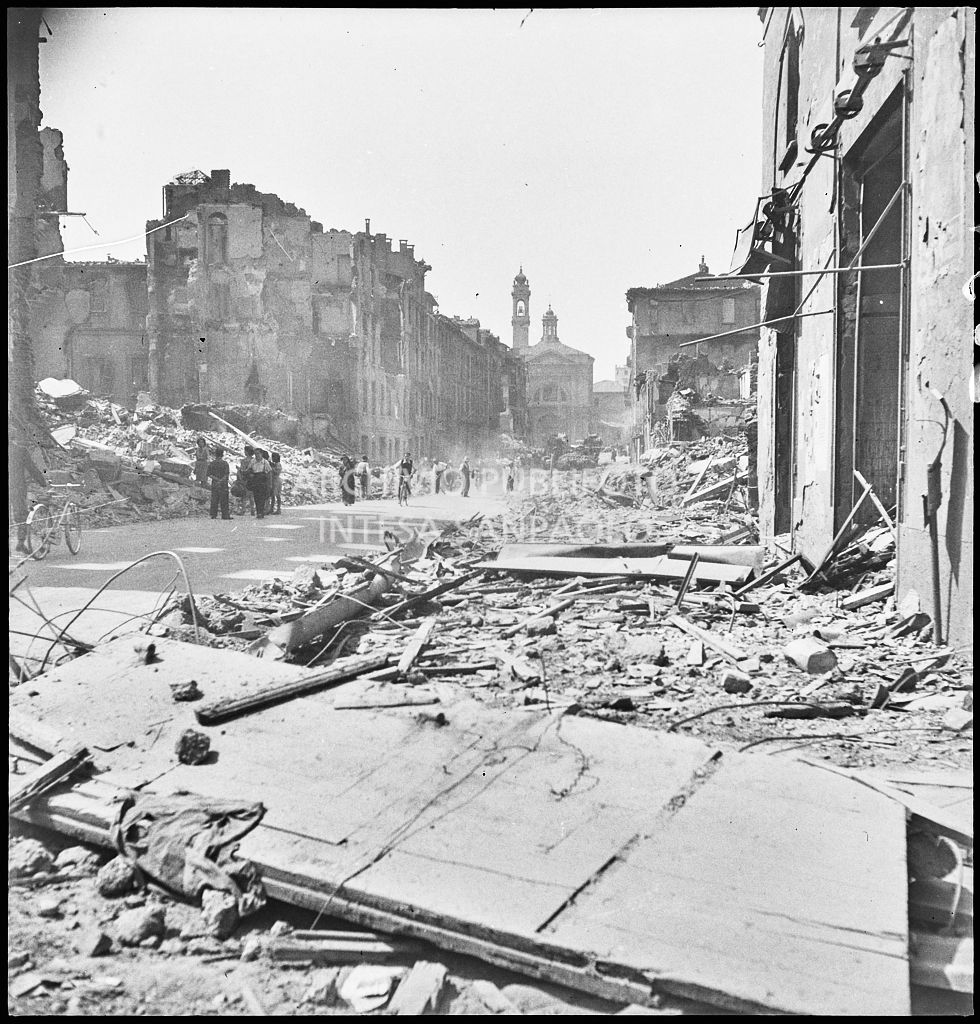 Scorcio di via Molino delle Armi a Milano con gli edifici distrutti dai bombardamenti. Le macerie sono state addossate ai lati della strada per consentire la circolazione nella via. Sullo sfondo la chiesa di Santa Maria della Vittoria