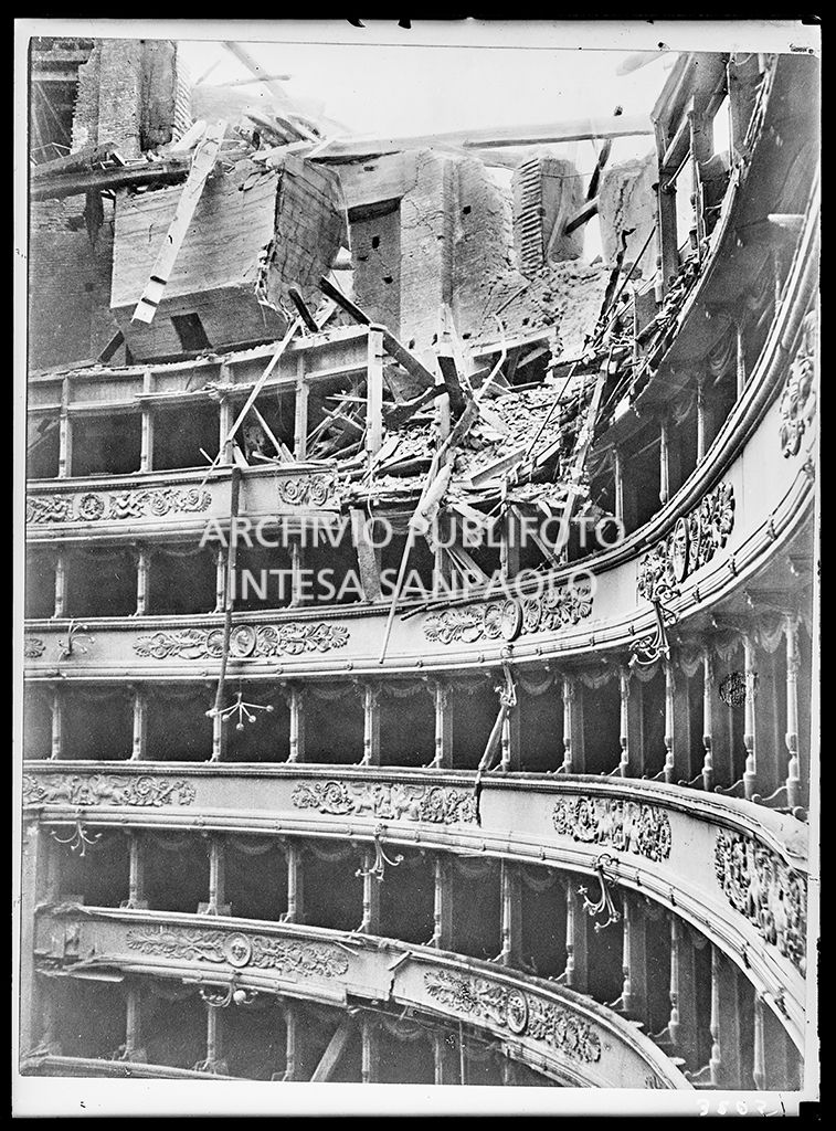Particolare dell'interno del Teatro alla Scala di Milano dopo i bombardamenti: il tetto e la volta centinata sottostante sono completamente crollati distruggendo in parte il quinto e sesto ordine di gallerie e danneggiando i palchi, il proscenio e la platea
