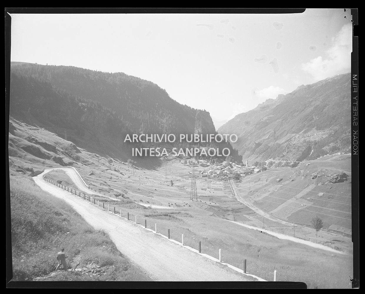 Strada tra le montagne con alcune case in valle<br>20154