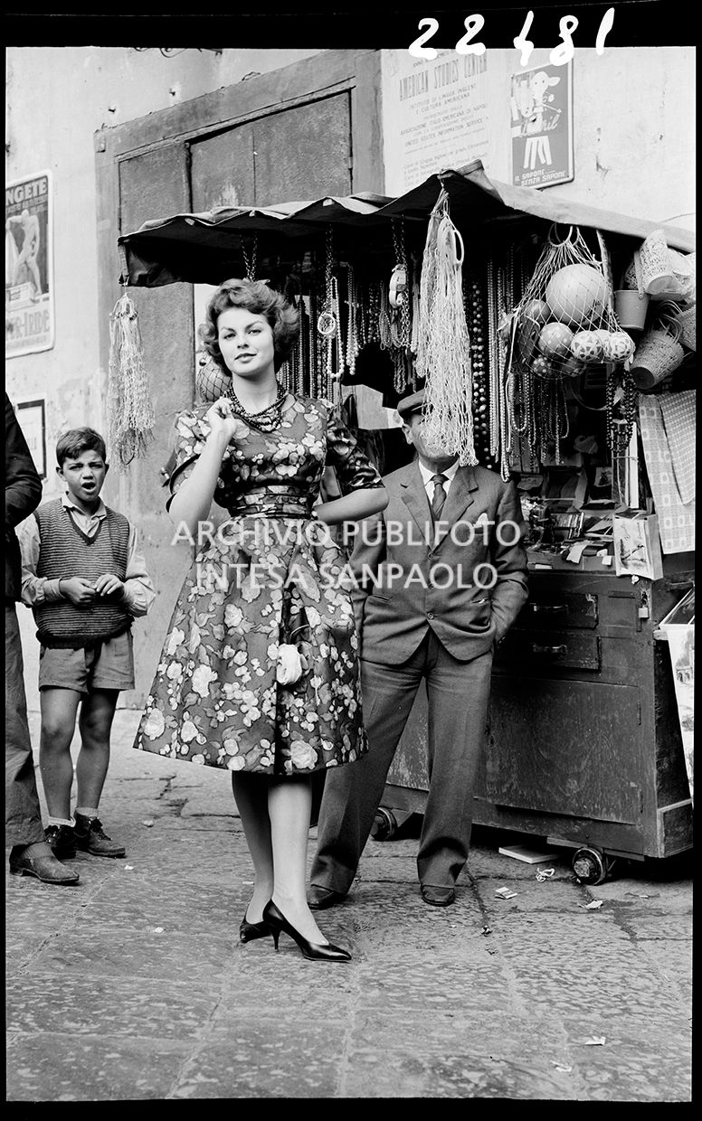 Indossatrice davanti ad una bancarella con abito a fiori e collana<br>22481