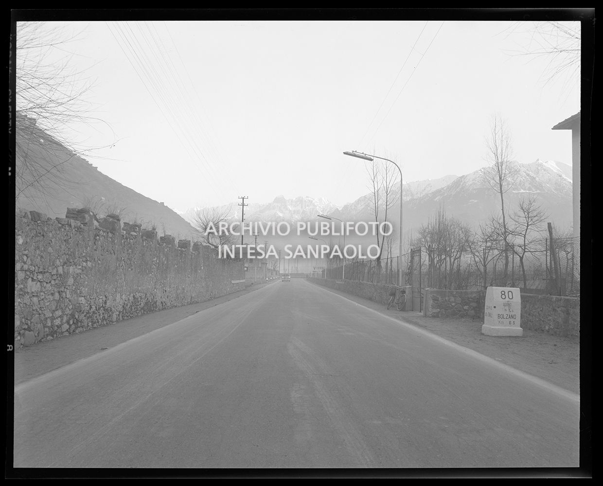 Strada di montagna con una pietra miliare con la scritta: "80 Cogno km 1,5 Bolzano km 165" (uguale allo scatto 25245)<br>25243