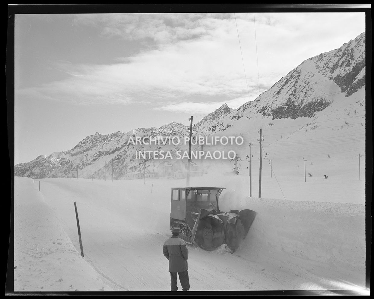 Spazzaneve in funzione su una strada mentre un uomo controlla il lavoro<br>25246