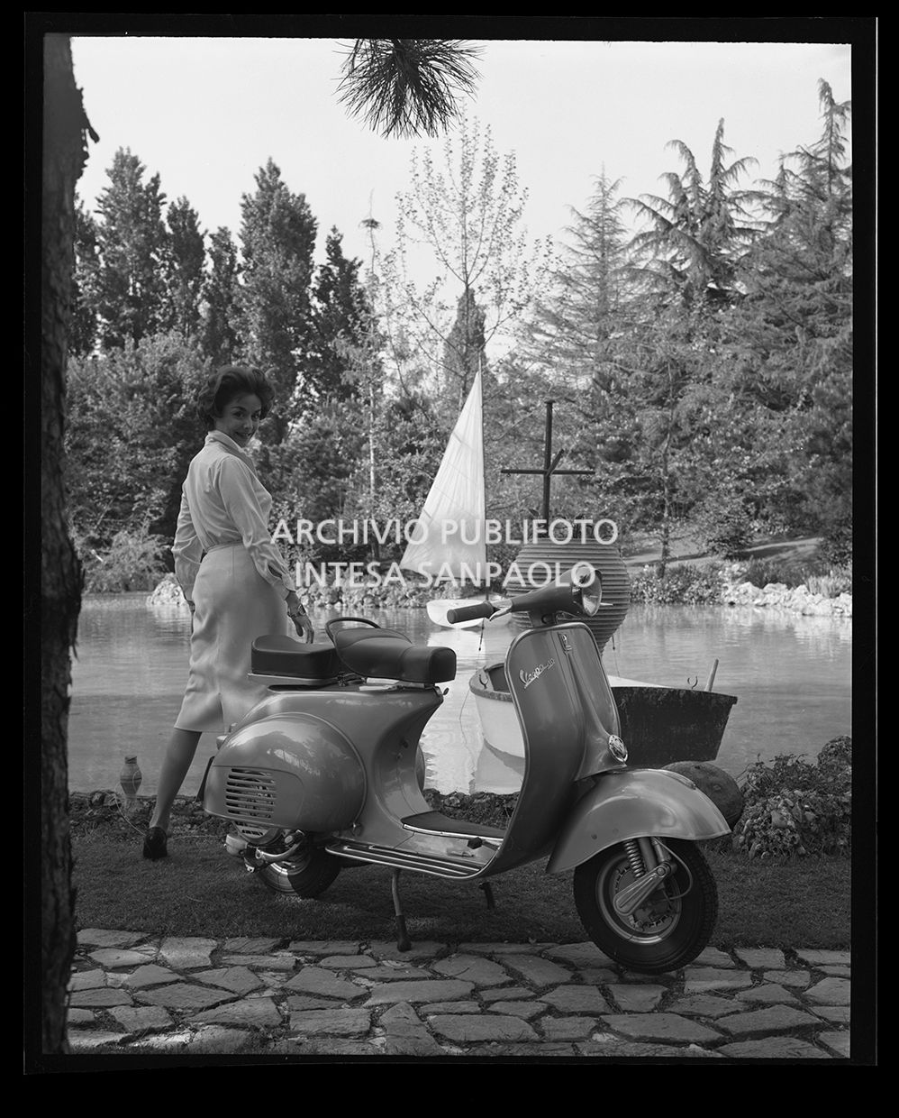 Vespa in riva ad un fiume con una donna<br>27506
