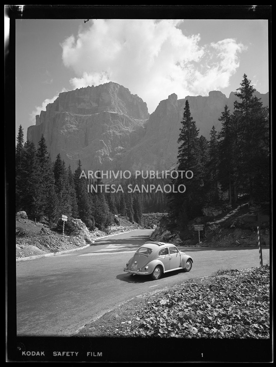 Strada con automobile. Su alcuni cartelli stradali si legge "Cortina d'Ampezzo","Passo Pordoi km 6" e "km 7 Passo Sella"<br>29906