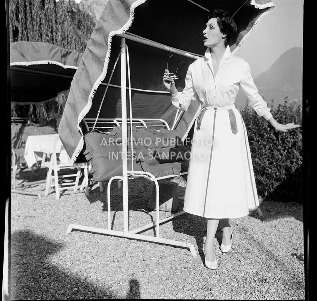 Indossatrice con camicia, gonna ampia e occhiali da sole davanti ad una panchina a dondolo<br>10849