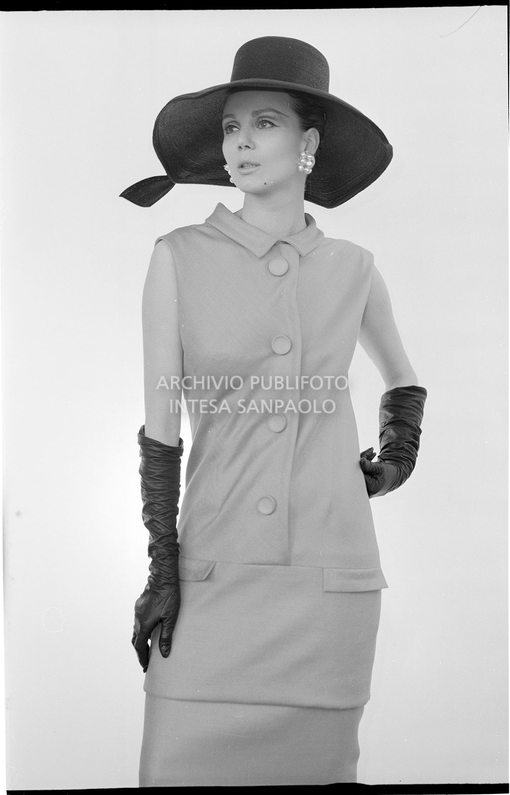 Indossatrice con abito sbracciato, guanti e cappello<br>10907