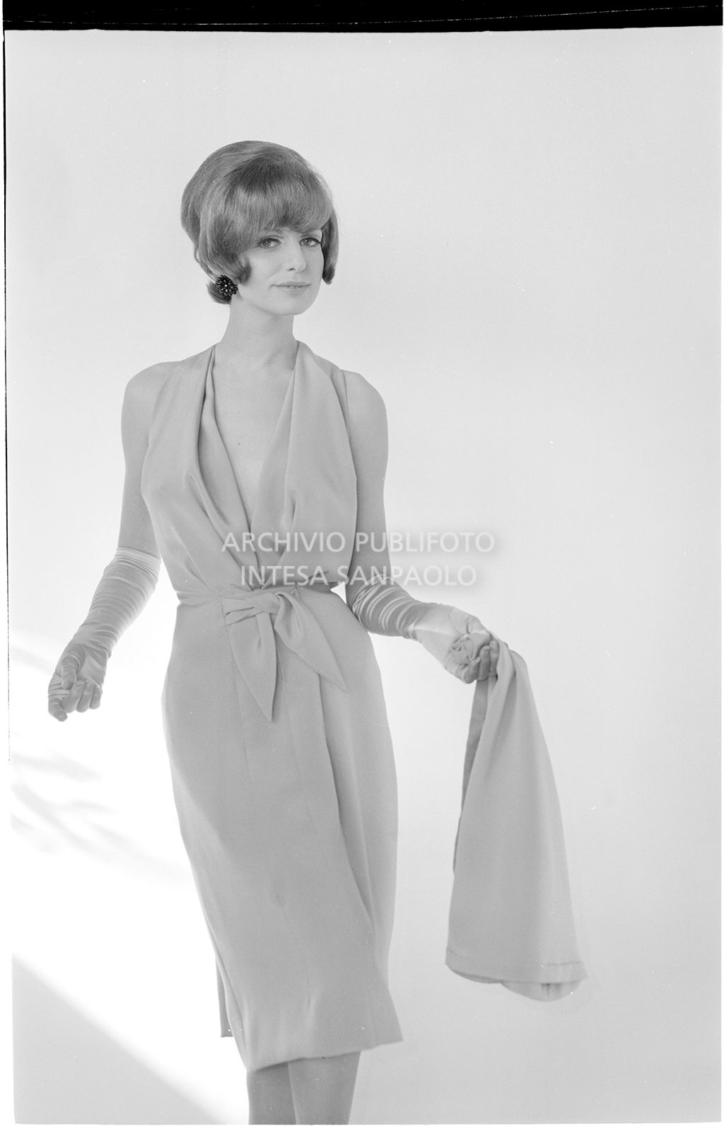 Indossatrice con abito con scollo all'americana, guanti e foulard in mano<br>10917