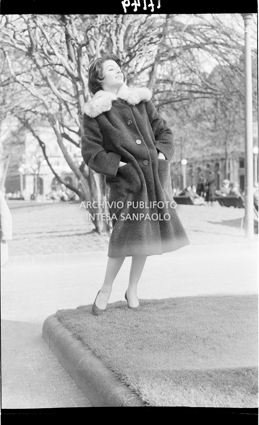 Indossatrice con cappotto e collo di pelliccia nel parco<br>17149