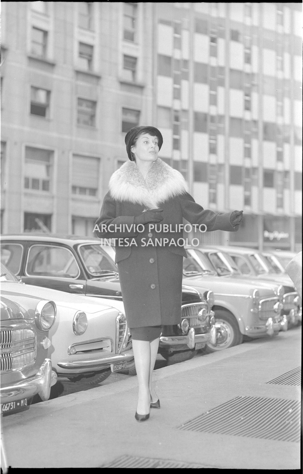 Indossatrice con cappotto con collo di pelliccia, guanti e cappello per strada<br>18523