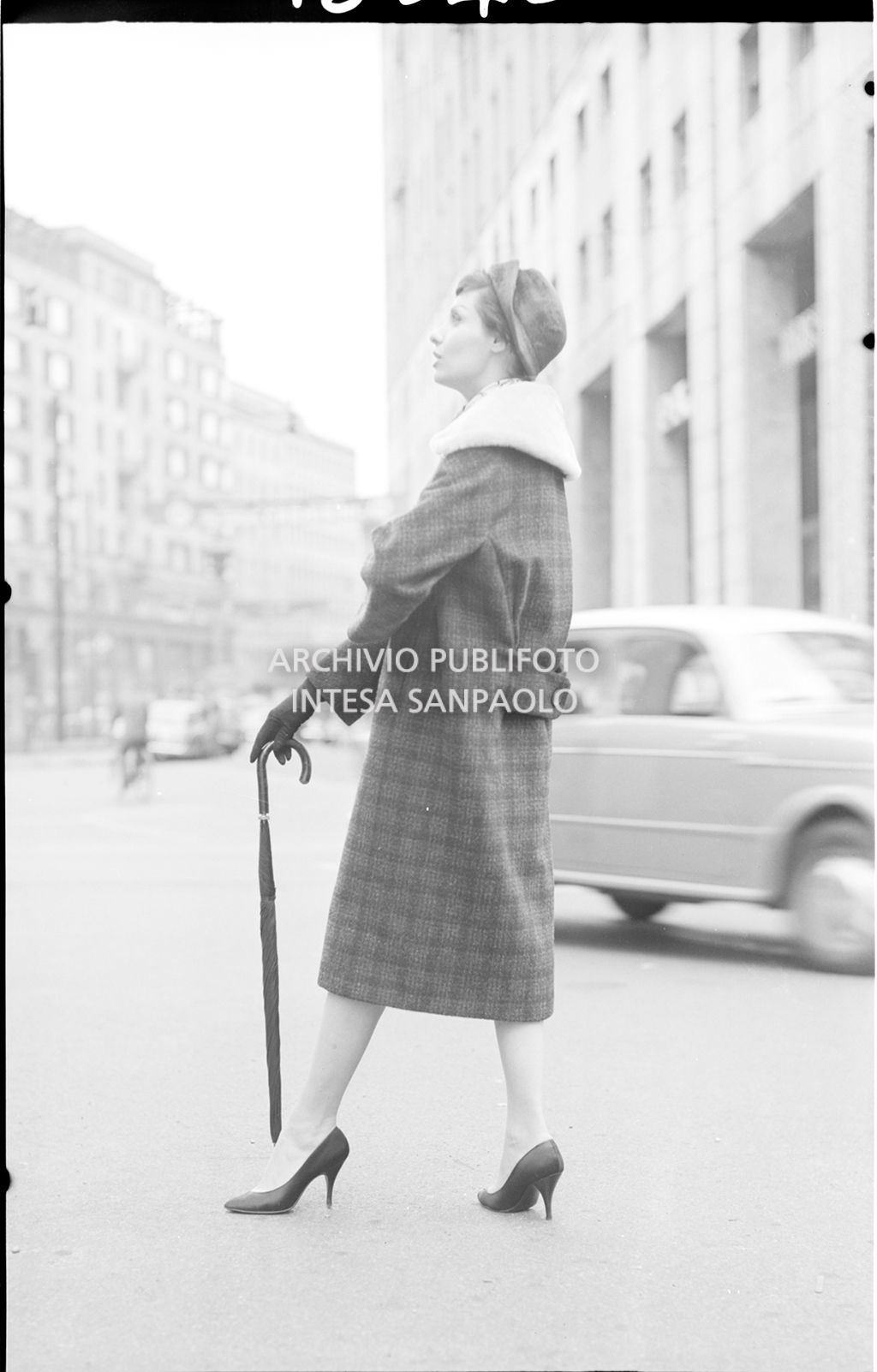 Indossatrice con cappotto con collo di pelliccia, guanti, cappello e ombrello per strada<br>18540