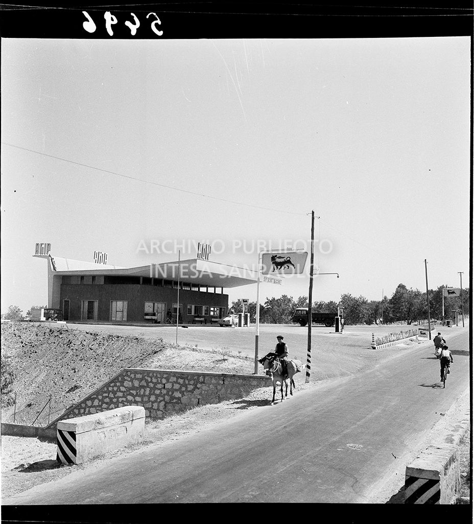 Strada con persone in bicicletta e a cavallo ed alle spalle il distributore<br>5496