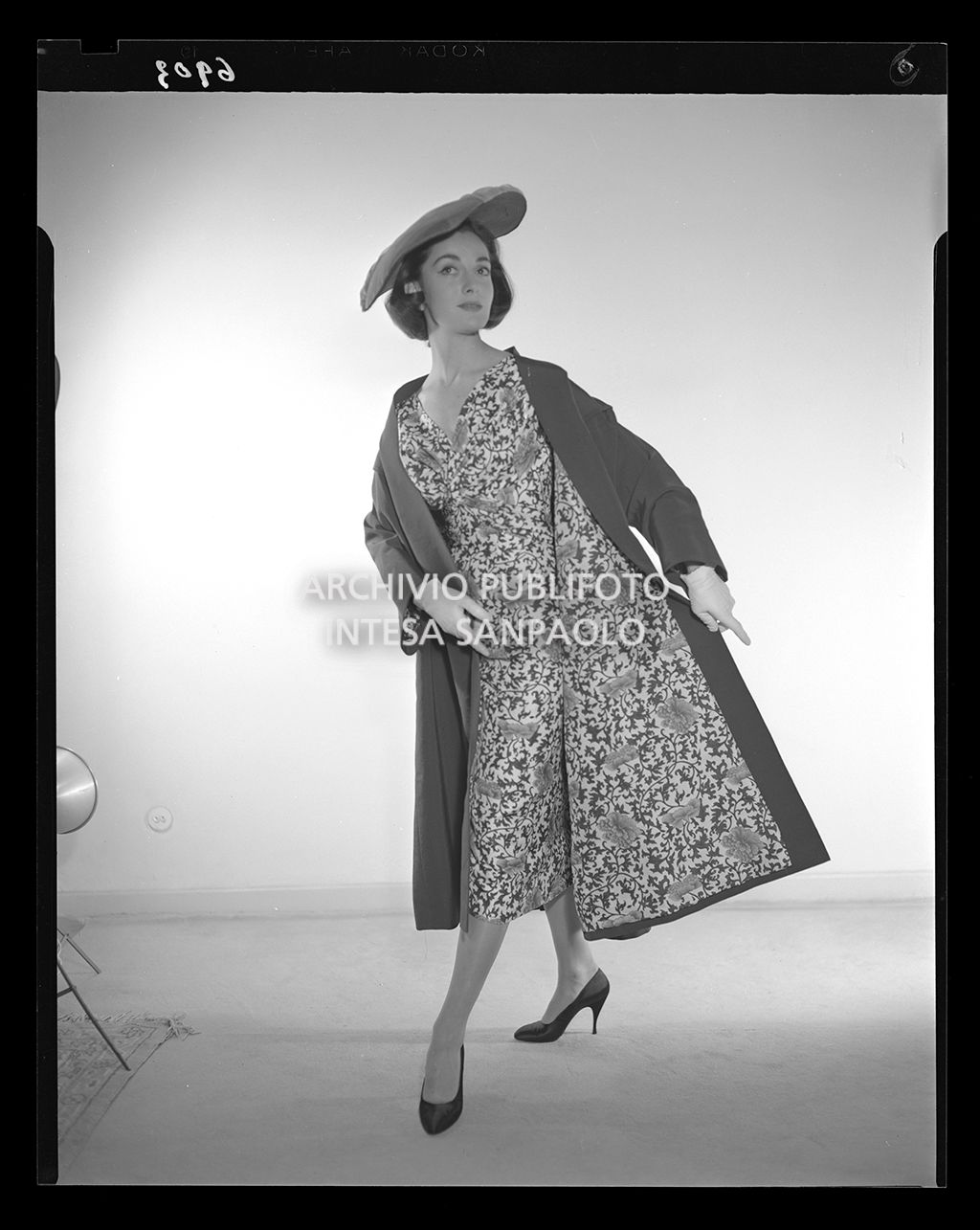 Indossatrice con abito al polpaccio, cappotto e cappello<br>6903