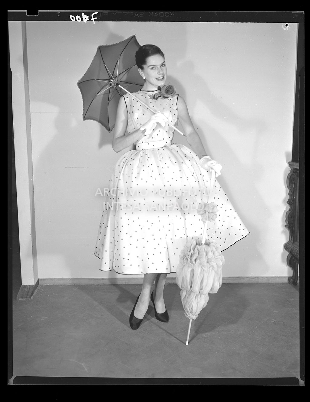 Stessa indossatrice dello scatto 7099 con lo stesso abito e accessori, con l'aggiunta di un altro ombrello da sole<br>7100