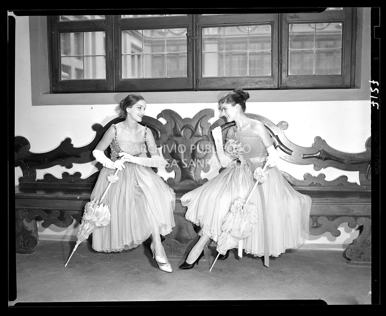 Due donne sedute con abiti drappeggiati al polpaccio, guanti e ombrelli da sole<br>7127