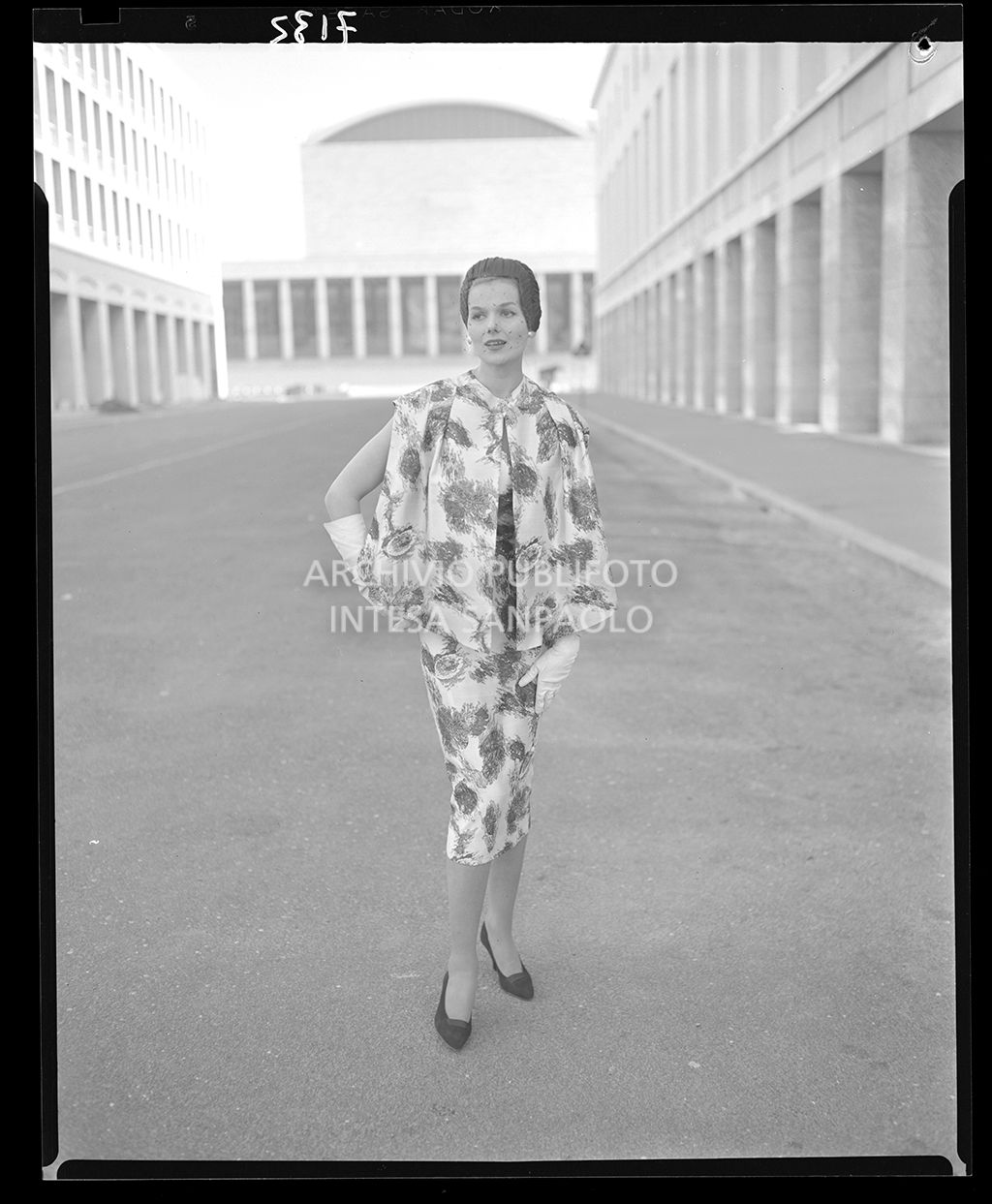 Donna con abito stretto al polpaccio con mantella della stessa stoffa fiorata e guanti<br>7133