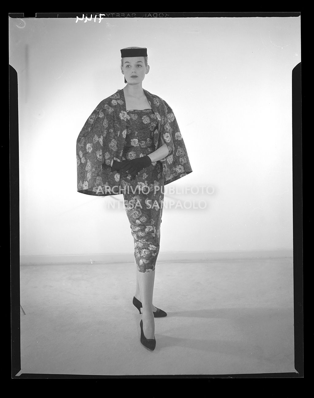 Donna con abito stretto al polpaccio con mantella della stessa stoffa fiorata e guanti<br>7144