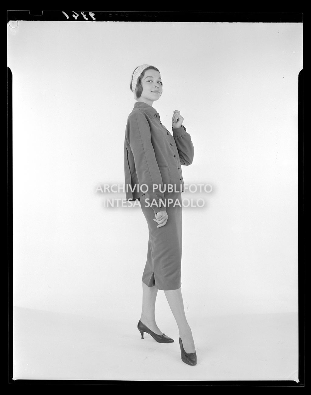 Indossatrice con tailleur con gonna al polpaccio e fascia in testa<br>9341